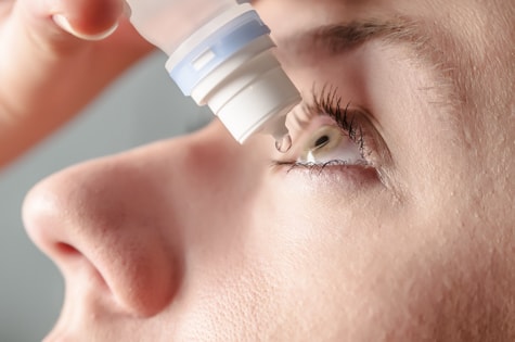Patient places eye drops into eye after epiretinal membrane surgery at Wolfe Eye Clinic.  