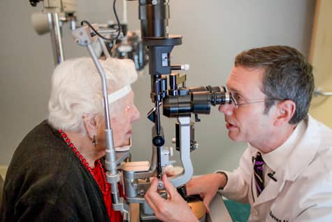 Iowa retina detachment specialist, Dr. Charles Barnes, performs vision exam on patient after reporting floaters in the eye.