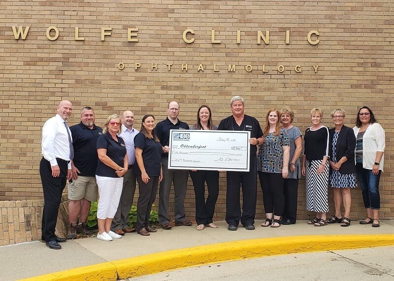 Wolfe Eye Clinic staff presenting Marshalltown Oktemberfest sponsorship check in Marshalltown, Iowa.